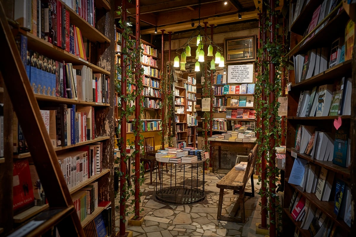 The interior of the Shakespeare and Company Bookshop in Paris in 2020. The wooden bookshelves are packed with books, and leaf-wrapped ladders help customers reach the tops of the shelves. 