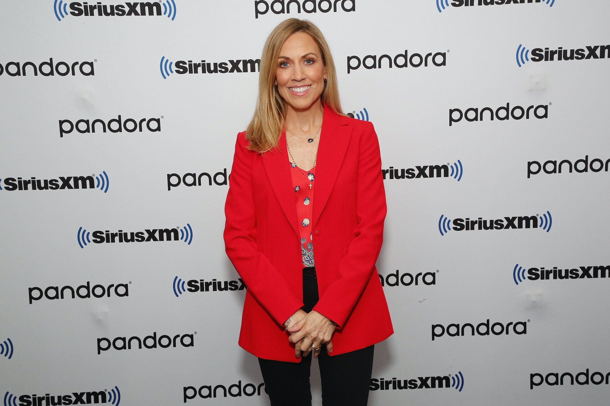 Sheryl Crow smiling in front of a white background