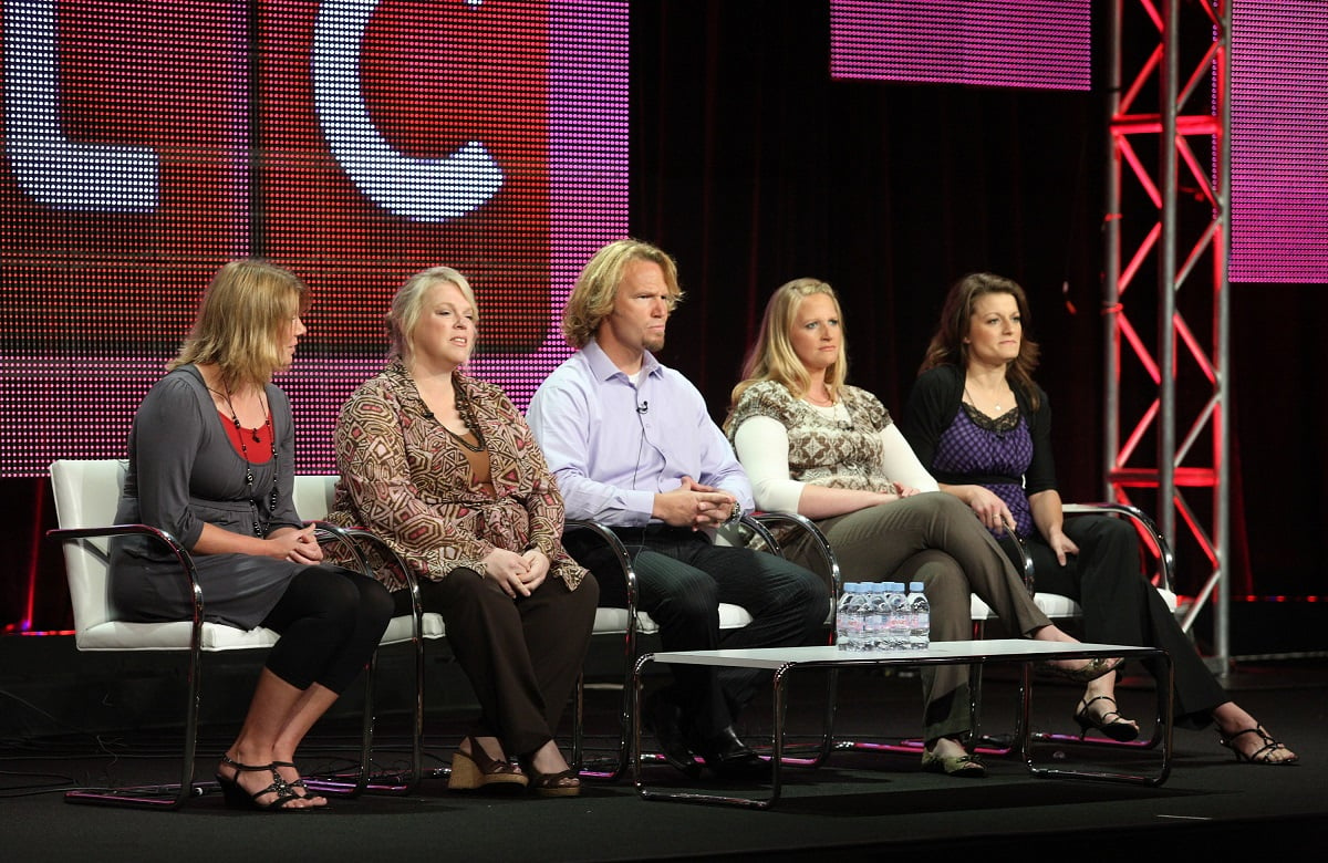 Kody Brown and his four wives sitting on stage at a TCA panel in 2010 in front of a TLC logo