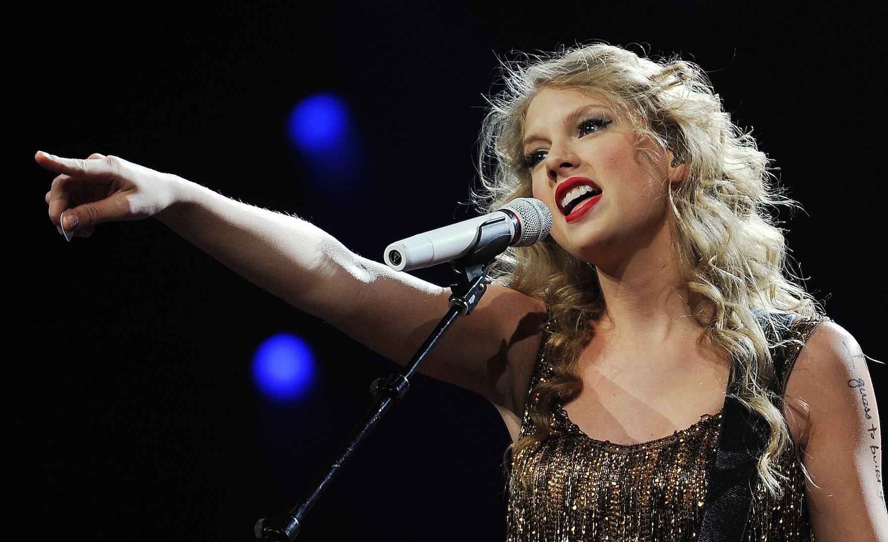 Taylor Swift performing on stage with her guitar