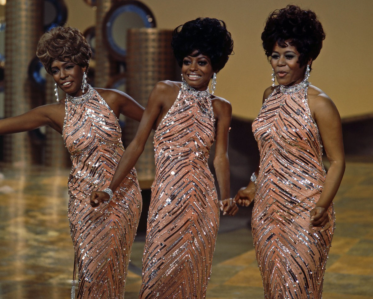 The Supremes (Cindy Birdsong, Diana Ross and Mary Wilson), wearing matching sequinned peach dresses with silver necklaces and earrings, during a live concert performance, circa 1965