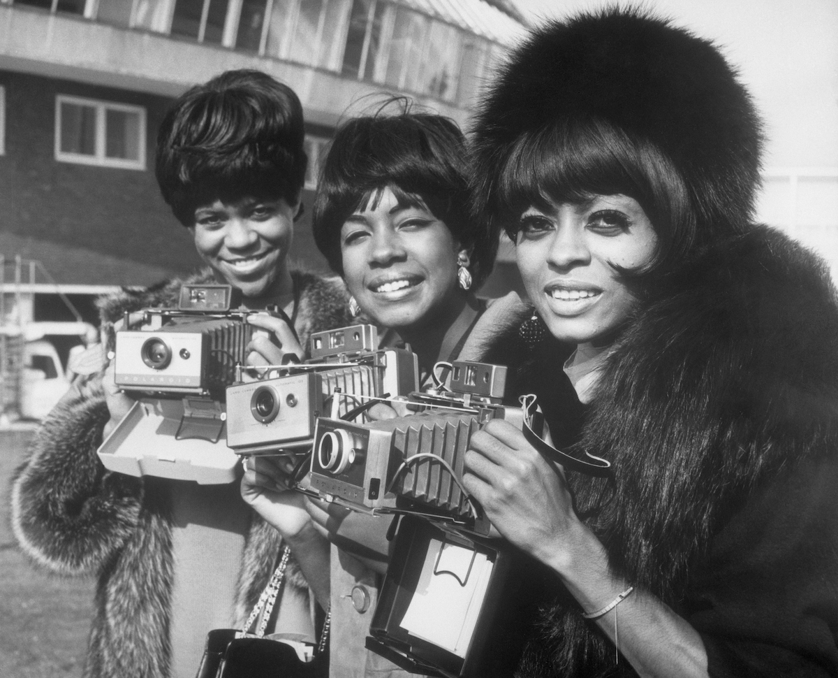 The Supremes, Florence Ballard, Mary Wilson, and Diana Ross pose with their cameras as they arrive at London Airport