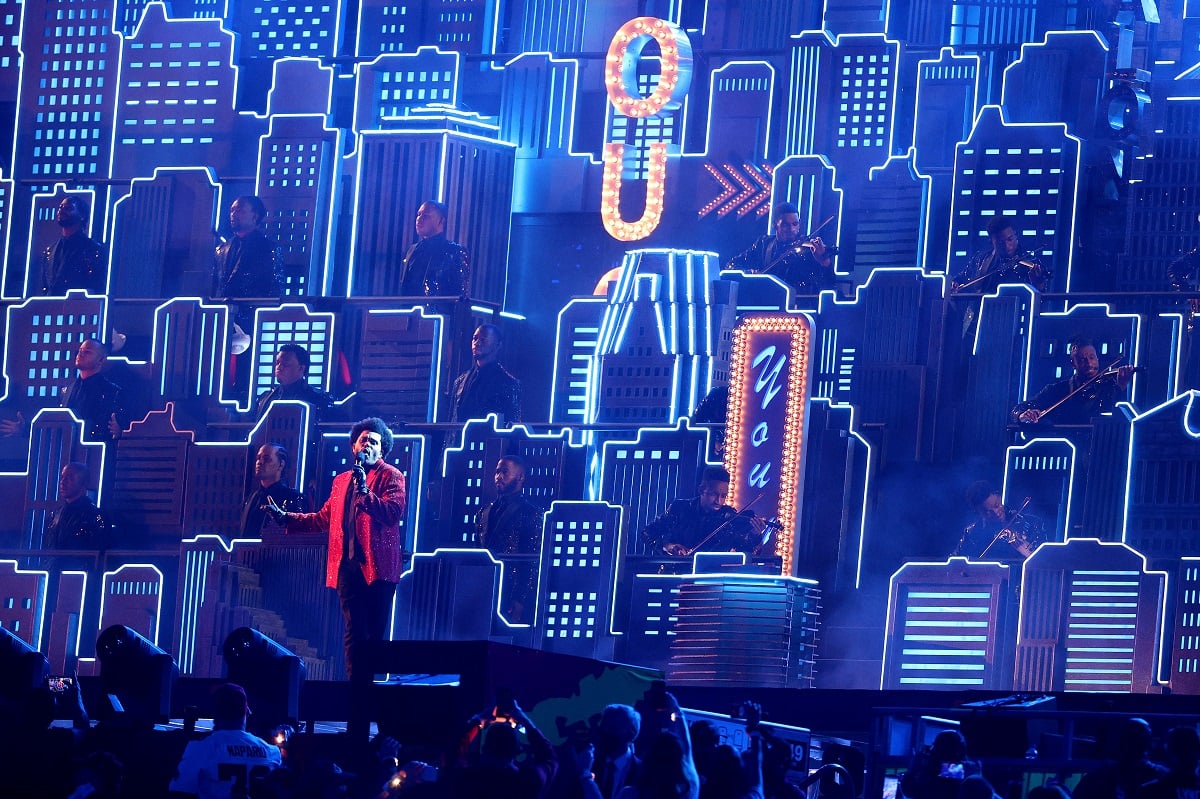 The Weeknd performing at the 2021 Super Bowl halftime show in front of a neon skyscraper backdrop