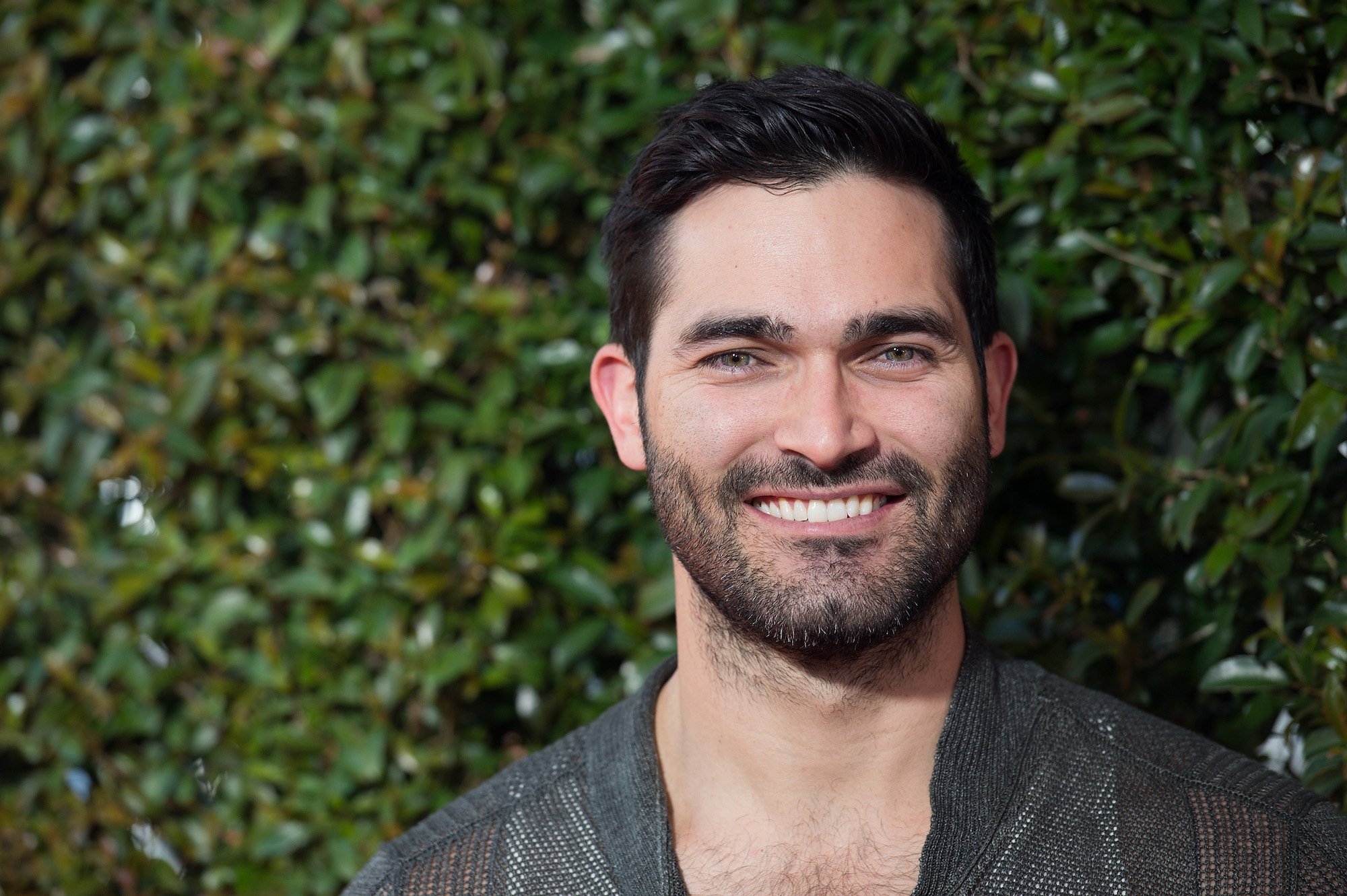 Tyler Hoechlin smiling in front of a green background