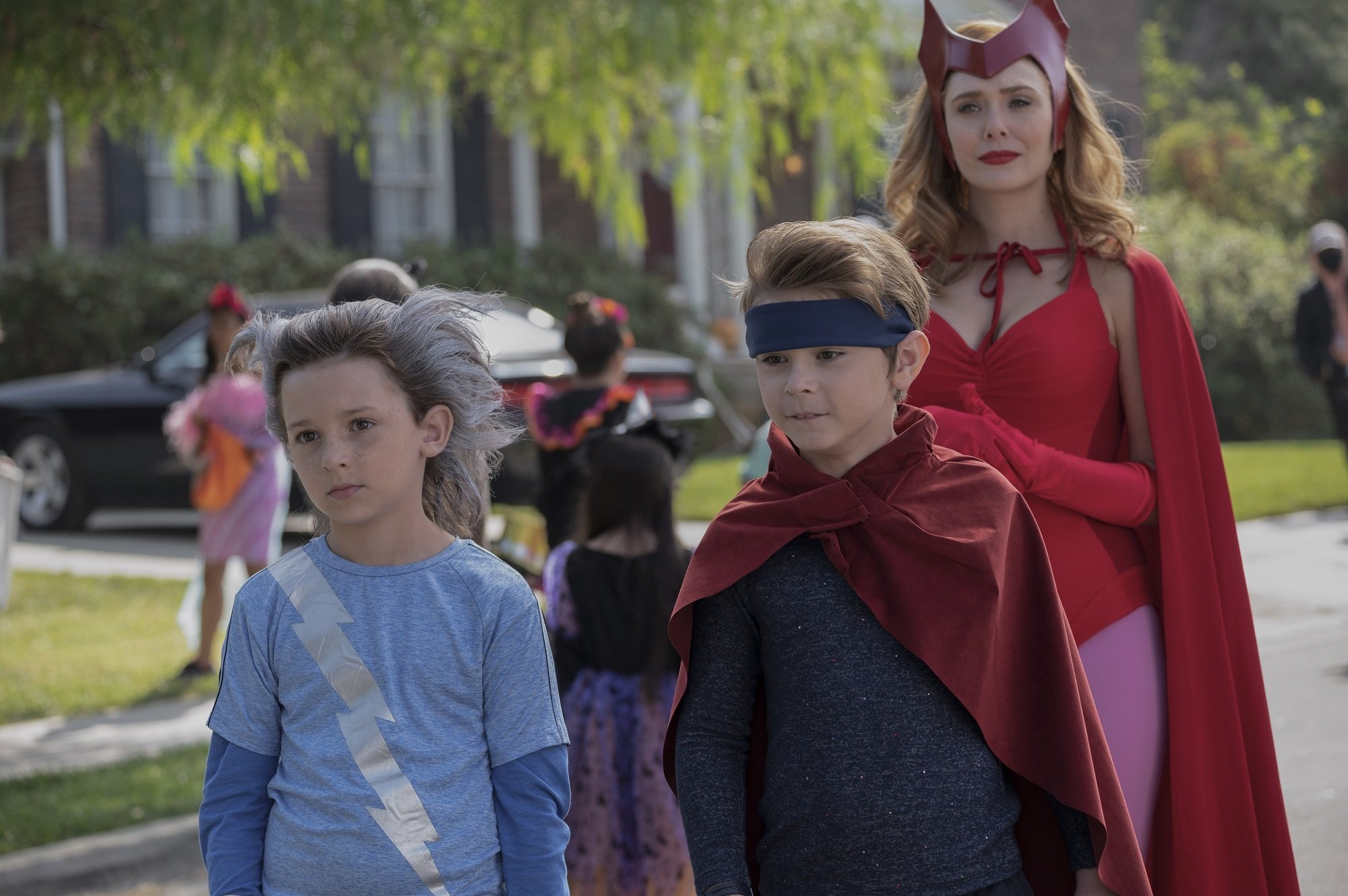 Julian Hilliard as Billy Maximoff, Jett Klyne as Tommy Maximoff, and Elizabeth Olsen as Wanda Maximoff wear Halloween costumes in 'WandaVision' on Disney+