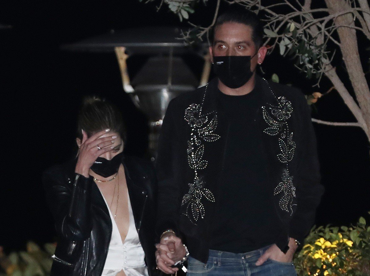 Ashley Benson and G-Eazy wearing black face masks and holding hands