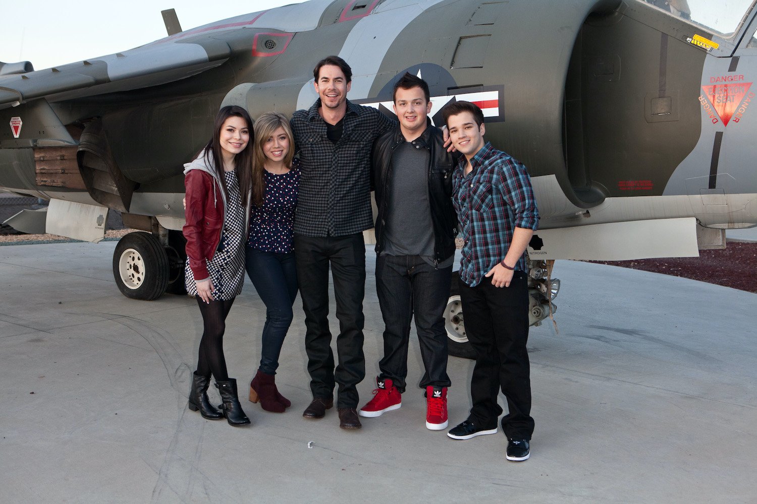 'iCarly' cast Miranda Cosgrove, Jennette McCurdy, Jerry Trainor, Noah Munck, and Nathan Kress pose in front of a plane in 2012