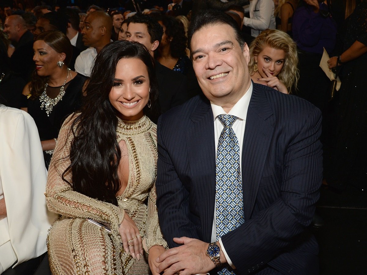 Demi Lovato holds hands with her dad, Eddie De La Garza, in front of a crowd
