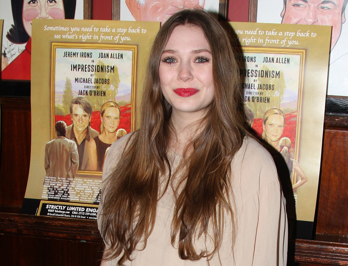 Elizabeth Olsen standing in front of a poster for her play 'Impressionism'