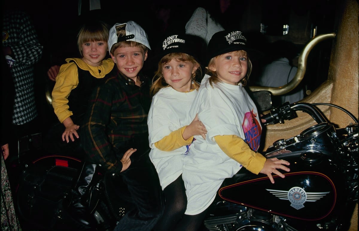Elizabeth Olsen with siblings Trent, Mary-Kate, and Ashley sitting on a motorcycle
