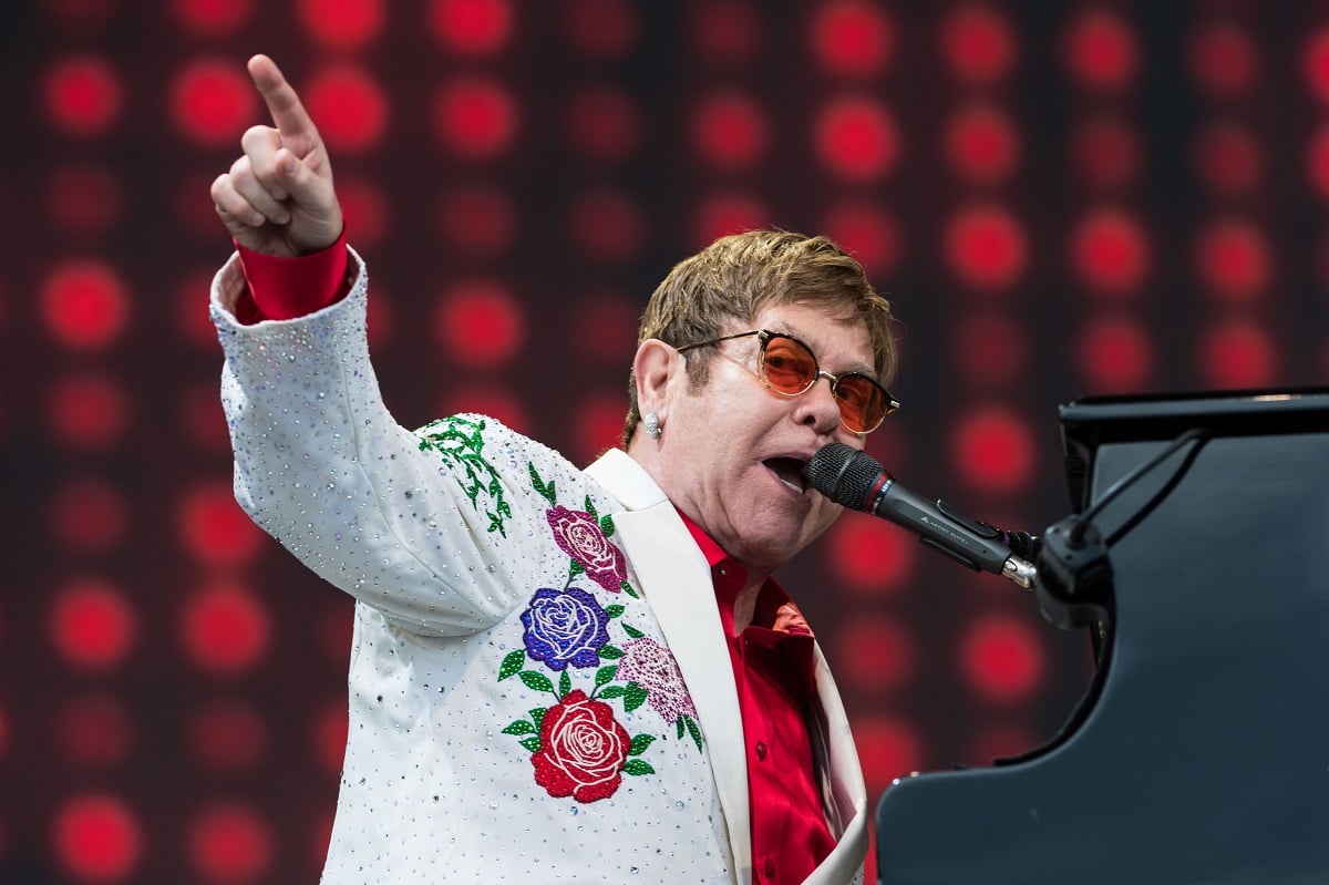 Elton John playing the piano and pointing