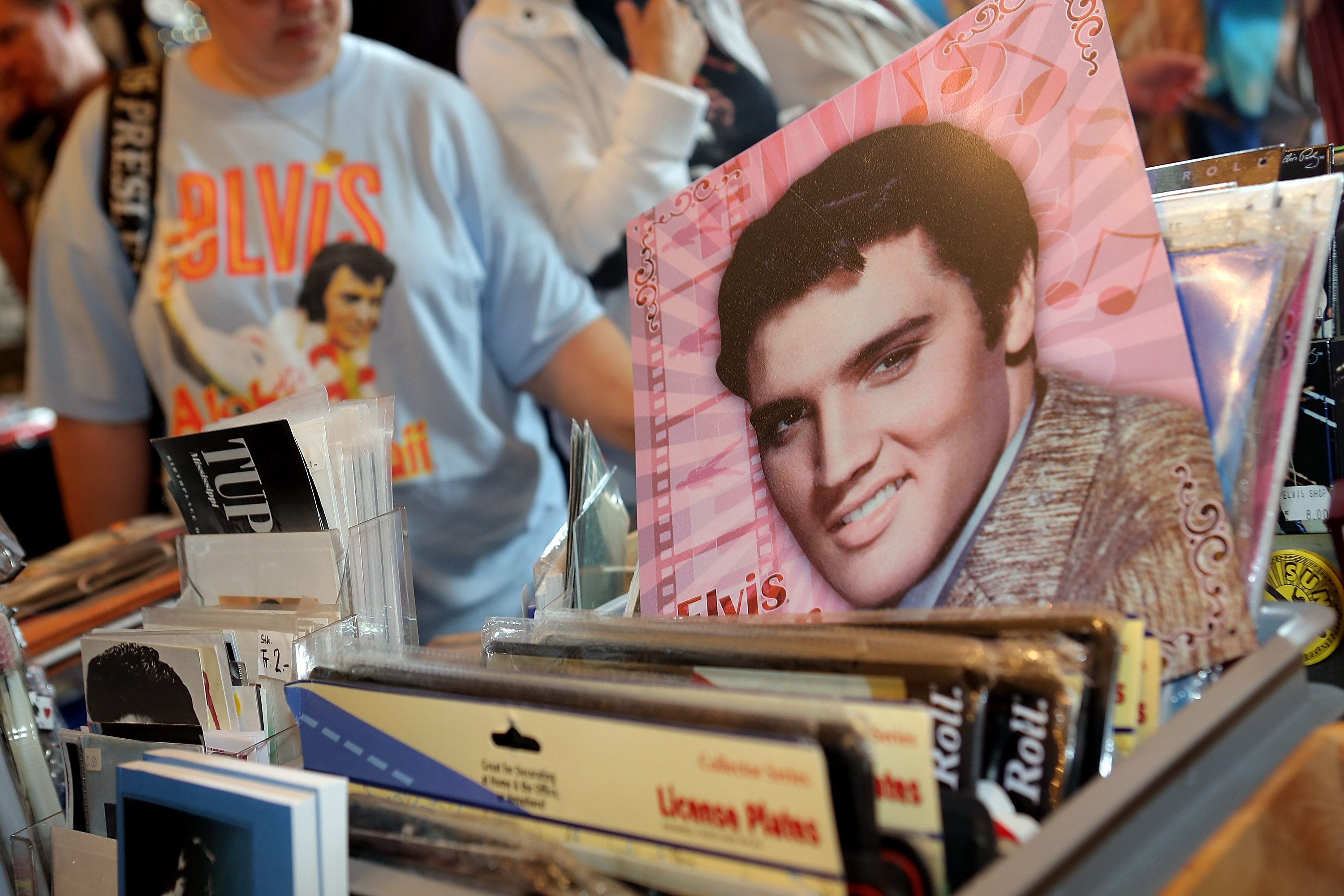 A headshot of Elvis Presley near someone wearing an Elvis shirt