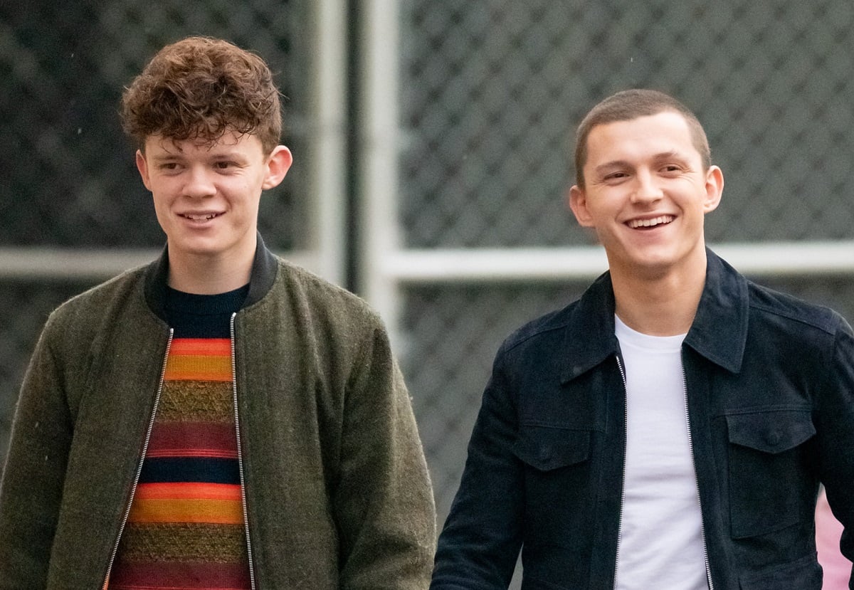 Tom Holland (R) and brother Harry Holland in front of a chain-link fence