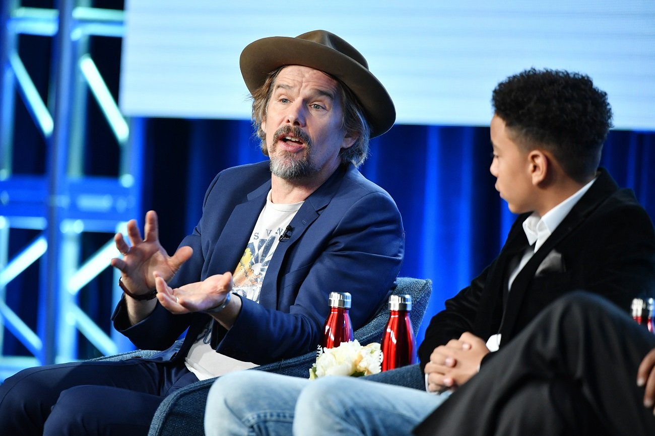 Ethan Hawke speaking while seated next to Joshua Caleb Johnson