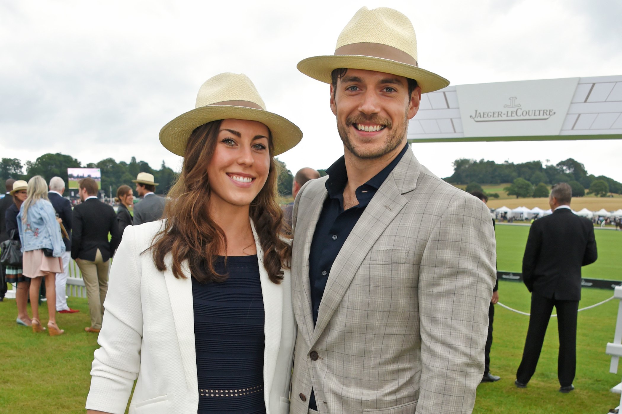 Henry Cavill's girlfriend, Lucy Cork, standing beside boyfriend Henry Cavill smiling at the camera outdoors