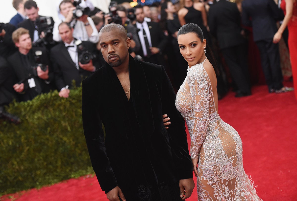 Kanye West (L) and Kim Kardashian posing on the red carpet in front of photographers