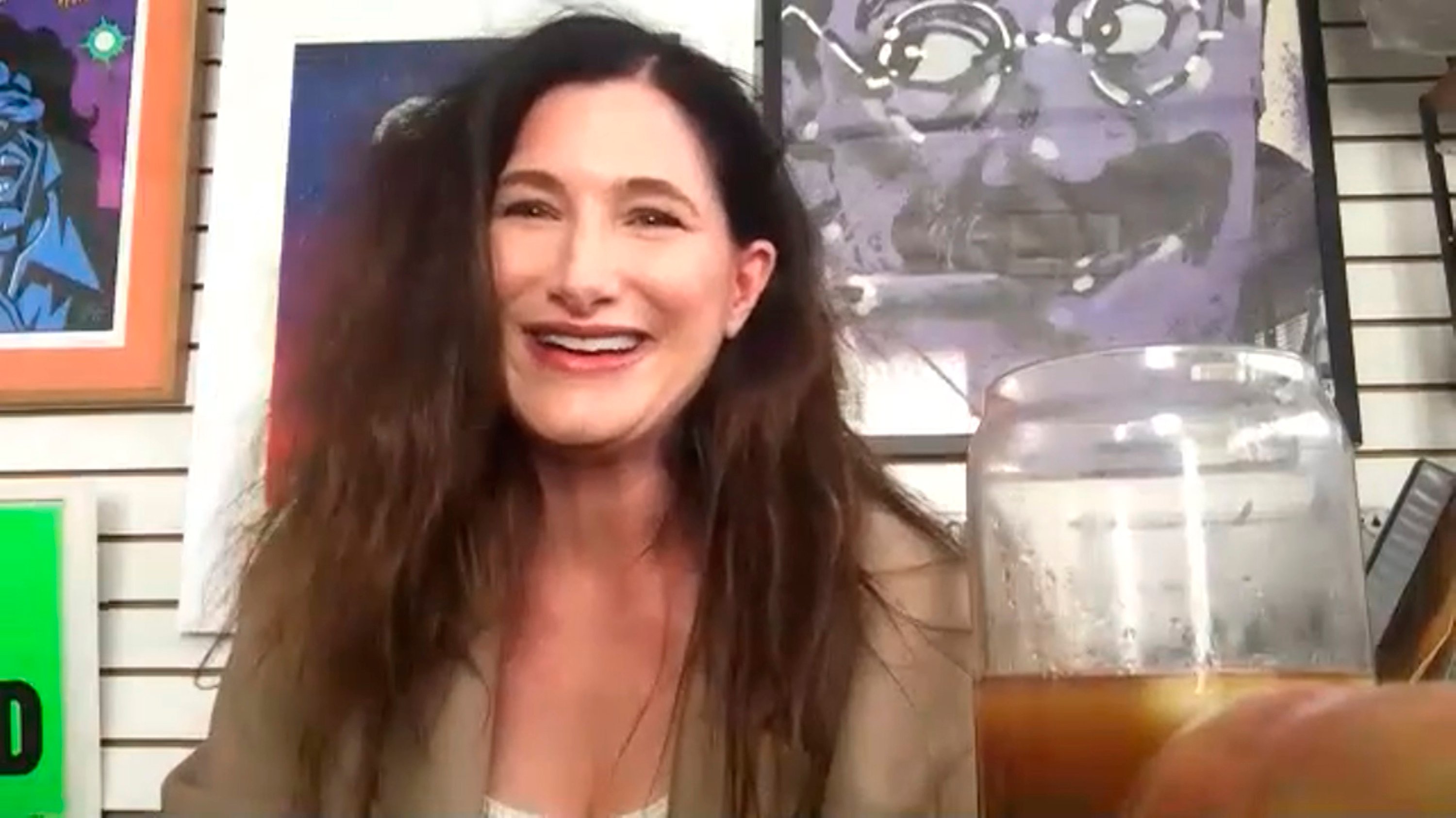 Kathryn Hahn in a Zoom interview with paintings behind her 
