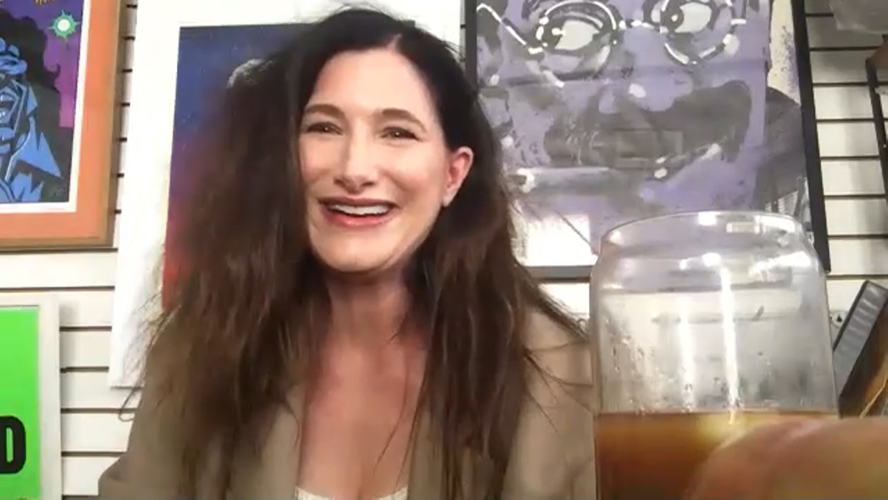 Kathryn Hahn in a Zoom interview with paintings behind her
