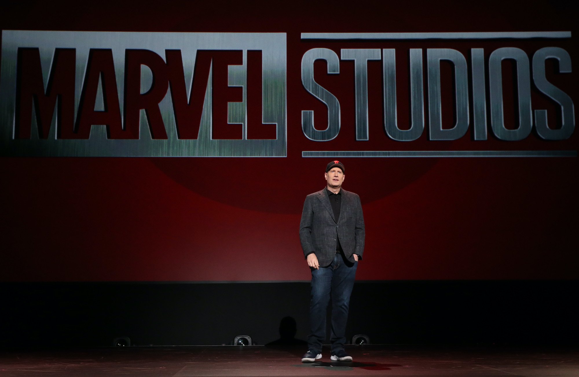 Marvel Studios president Kevin Feige stands on stage presenting new announcements to an audience