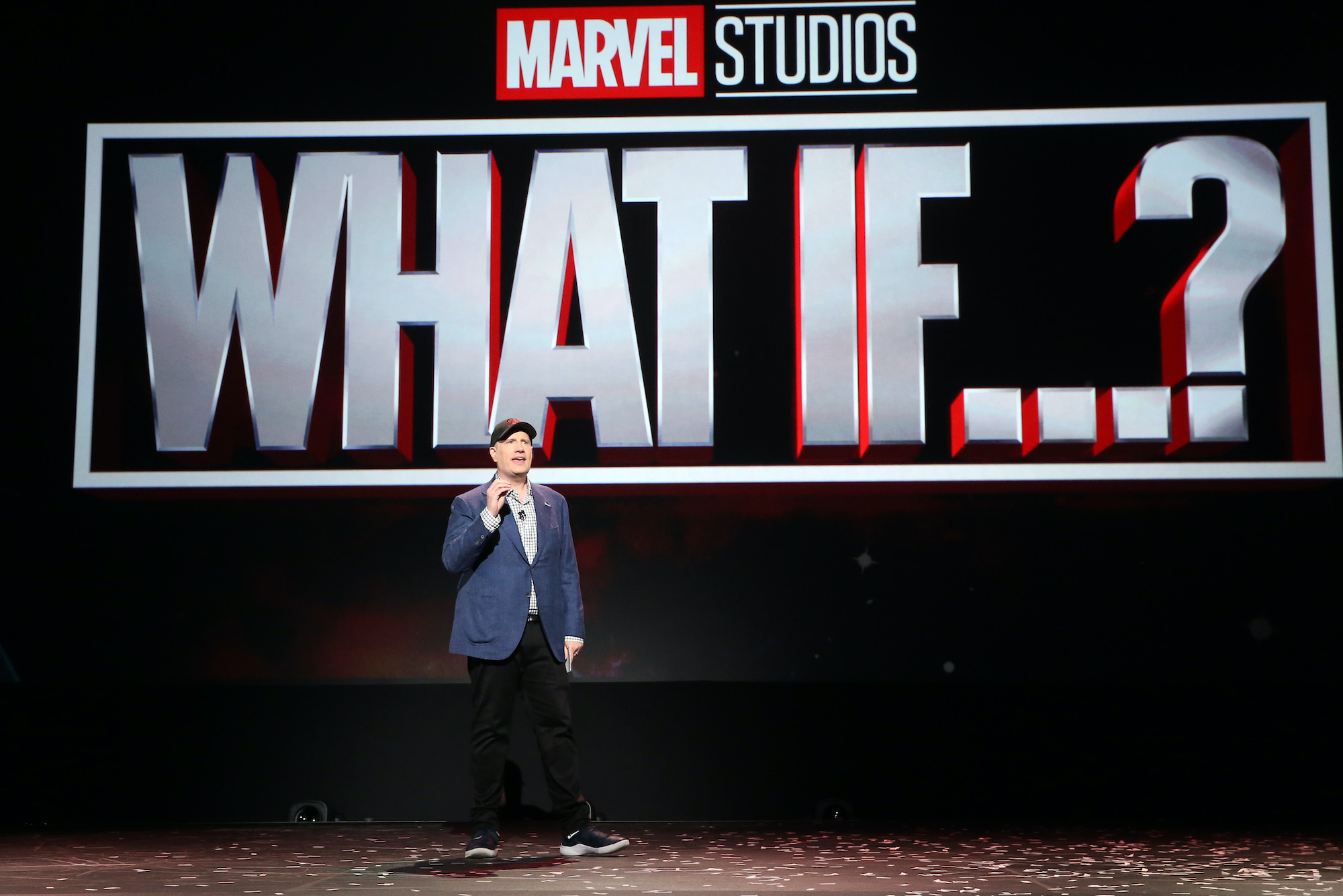 Kevin Feige stands onstage and speaks to an audience