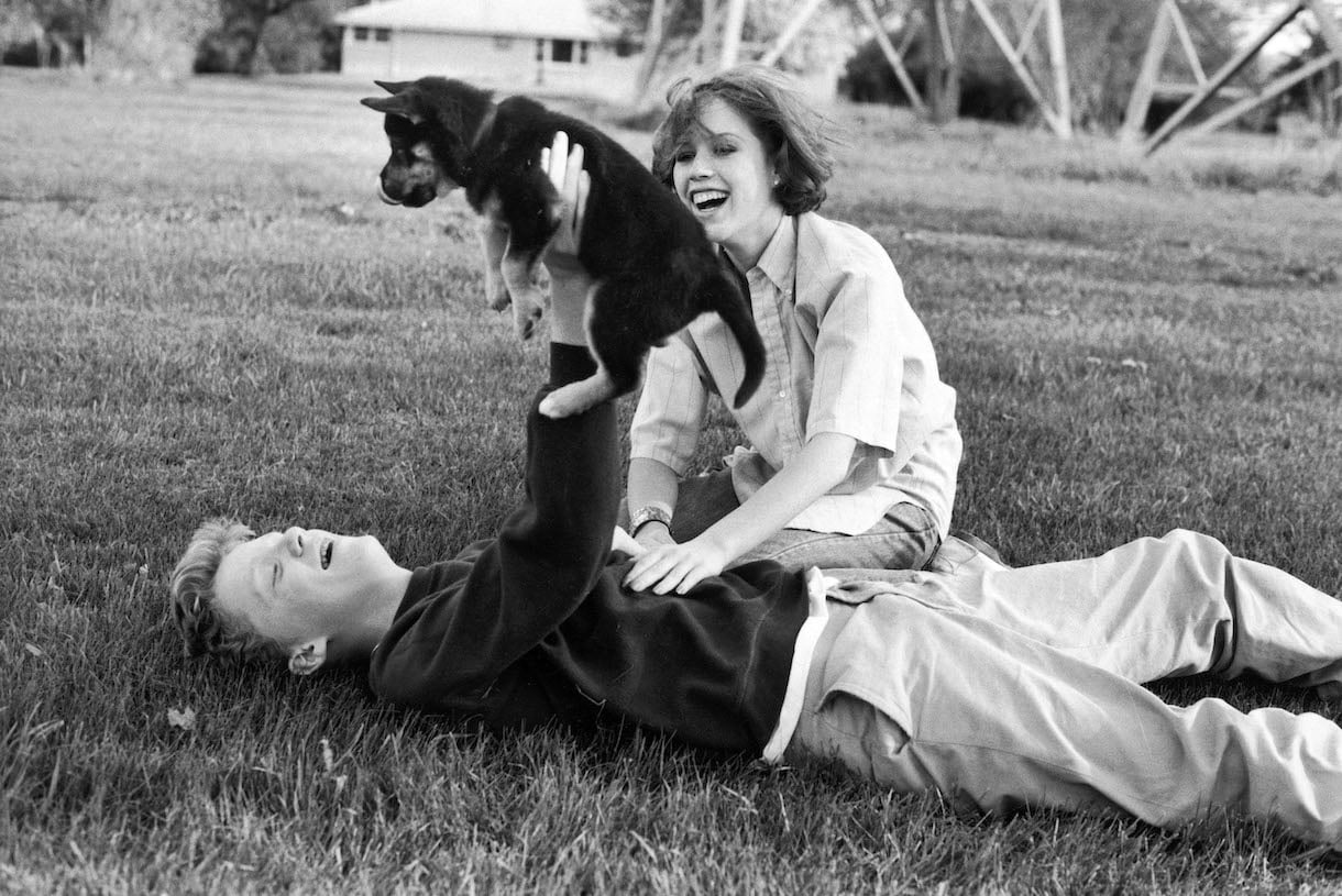 Actors Anthony Michael Hall and Molly Ringwald playing w. puppy during break in location shooting of 'The Breakfast Club'