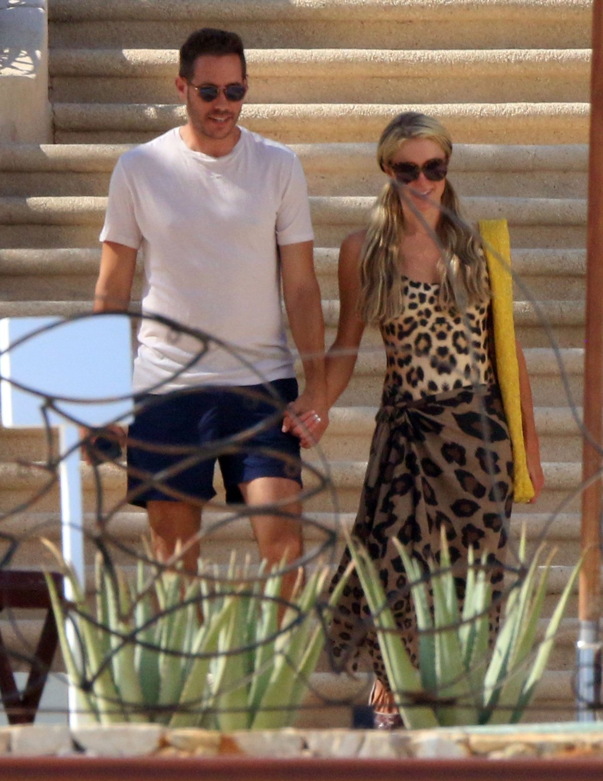 Paris Hilton and Carter Reum hold hands as they walk down a flight of stairs