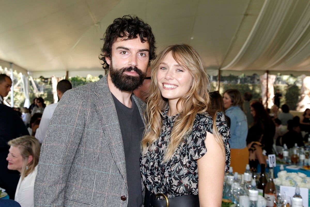 Robbie Arnett and Elizabeth Olsen smile in front of a crowd of people