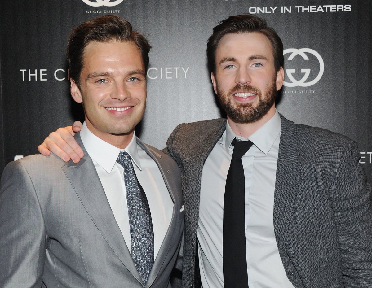 Chris Evans (R) with his arm around Sebastian Stan, both in gray suits