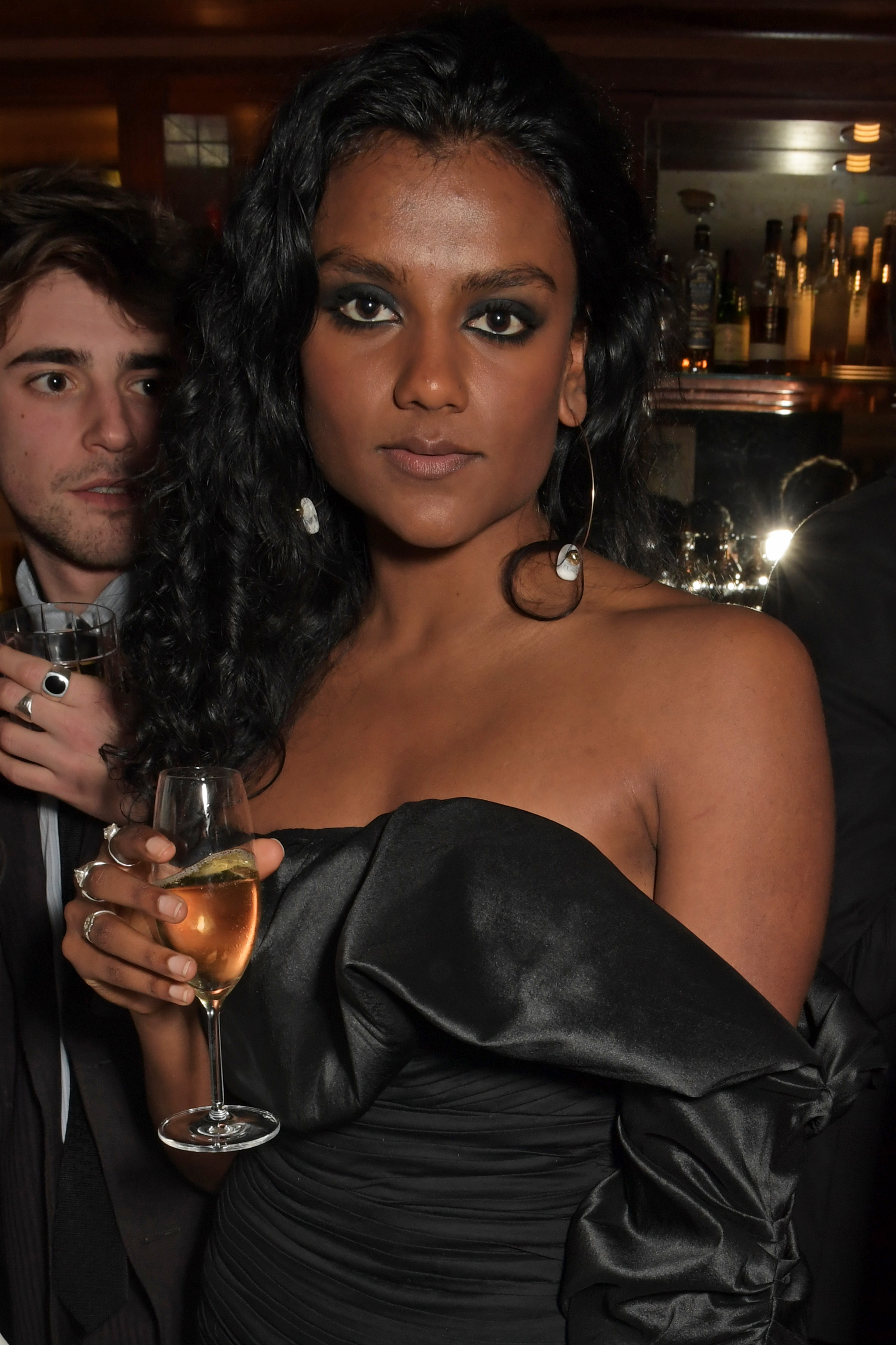 Simone Ashley in black dress holding a glass of wine