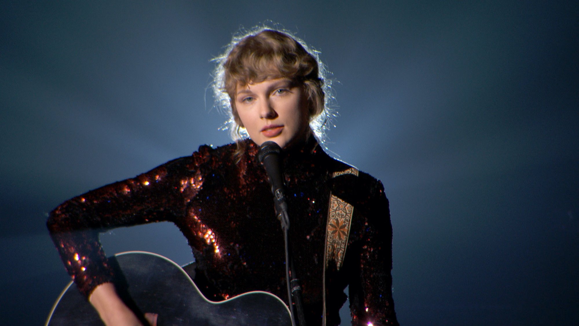 Taylor Swift performs onstage with her guitar