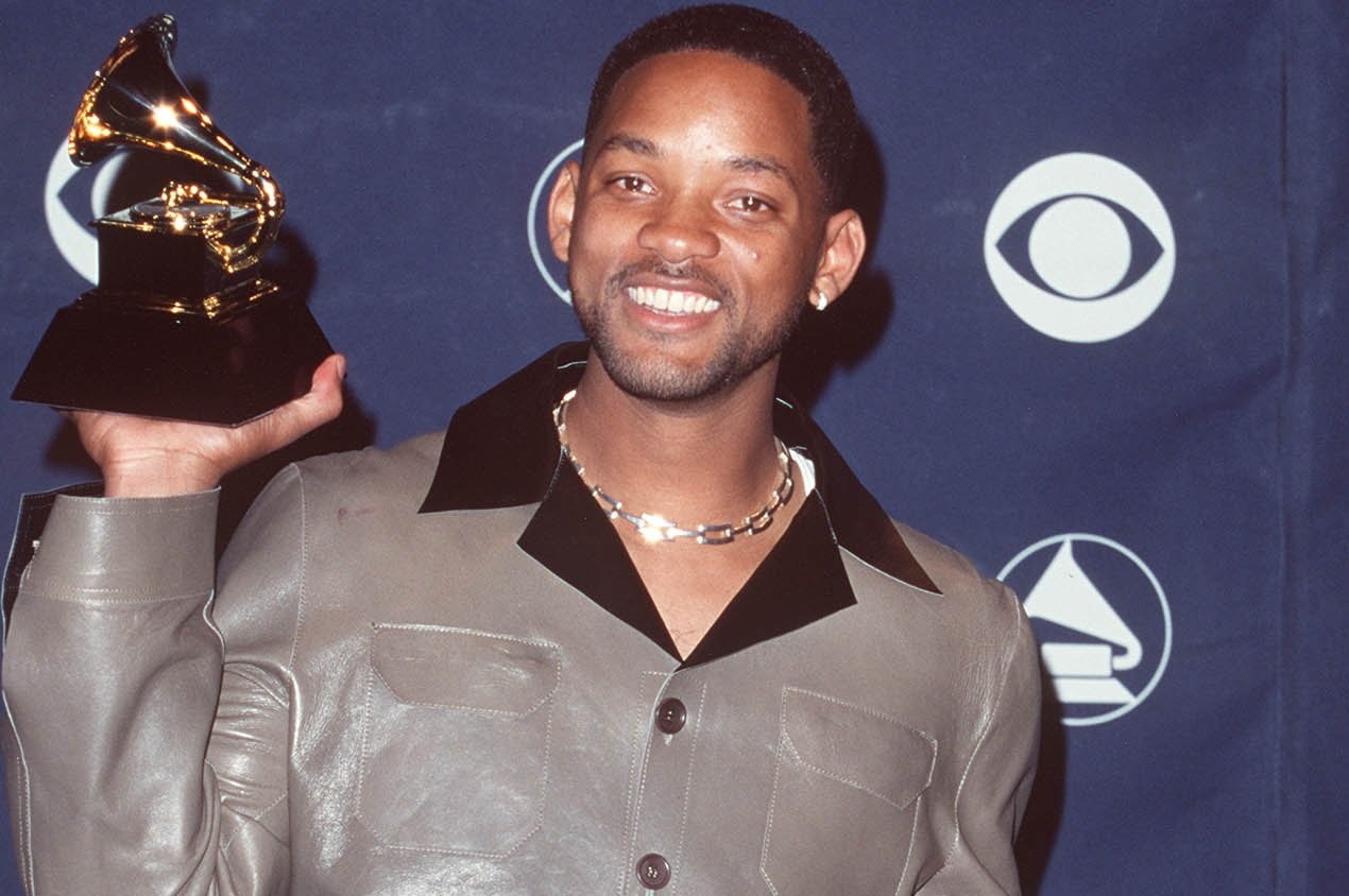 Will Smith holds a Grammy award and smiles for the camera