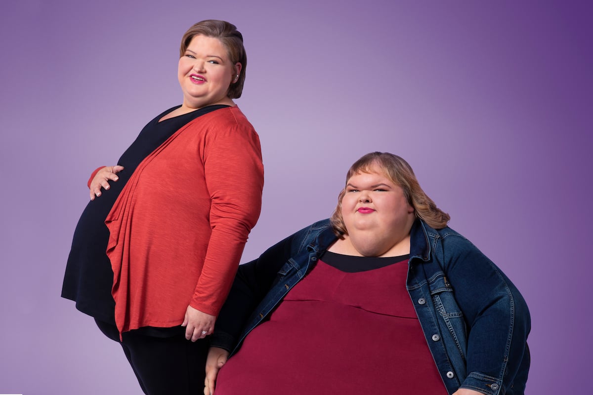 1000-Lb Sisters Season 3 stars Tammy Slaton and Amy Slaton -- the two sisters pose, a pregnant Amy Slaton standing next to Tammy Slaton. 