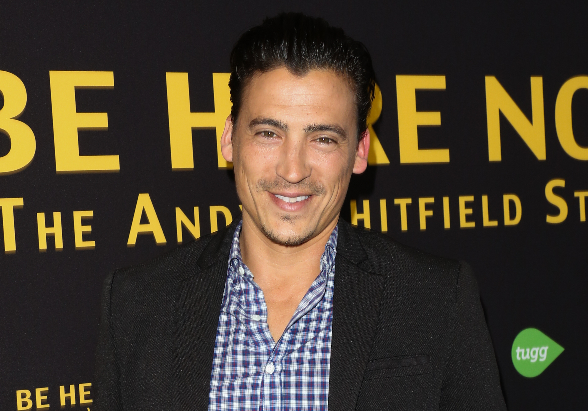Andrew Keegan smiling in front of a black background