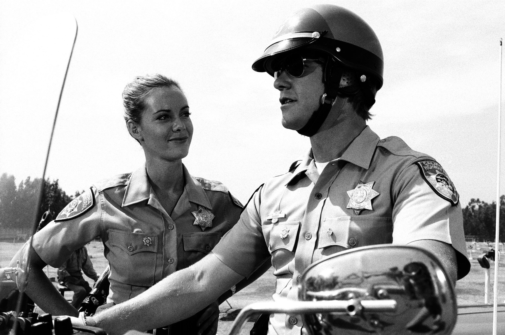 A black-and-white photo of actors Anne Lockhart as Officer Kathy Mulligan and Larry Wilcox as Officer Jon Baker in 'CHiPs,' Episode 7, "Return of the Supercycle," aired on October 27, 1979
