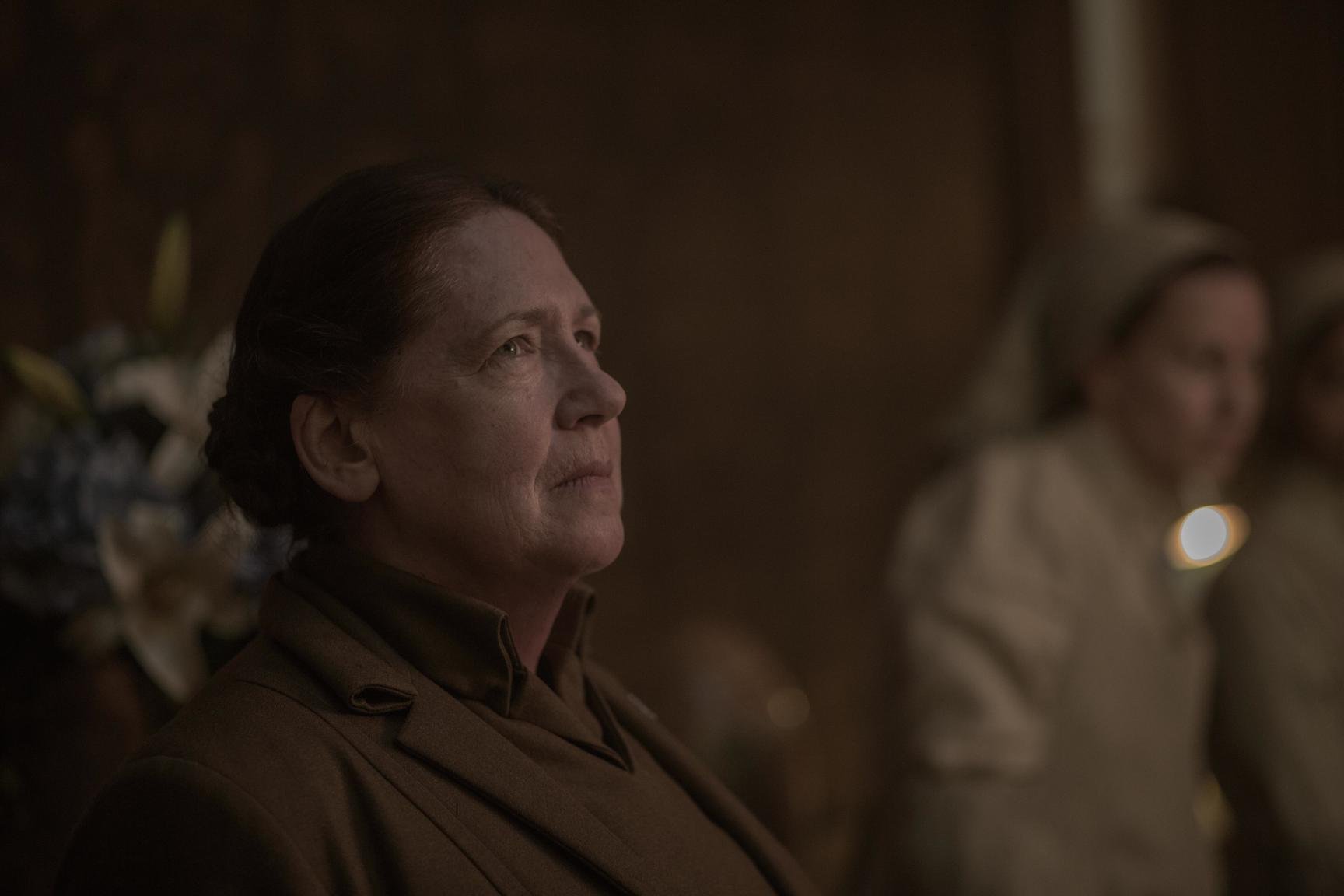 Ann Dowd, a member of 'The Handmaid's Tale' cast, playing Aunt Lydia in season 3. Aunt Lydia is looking up as someone speaks to her.