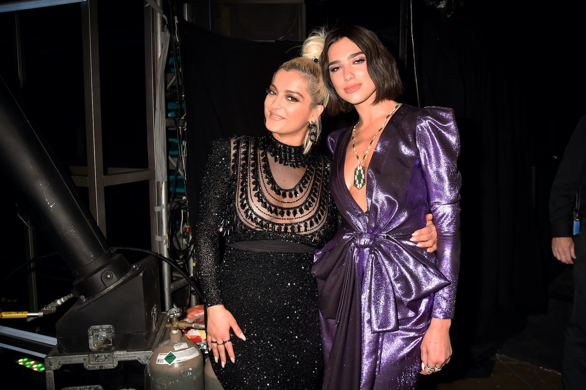 (L-R) Bebe Rexha and Dua Lipa, embracing, in the wings of a stade