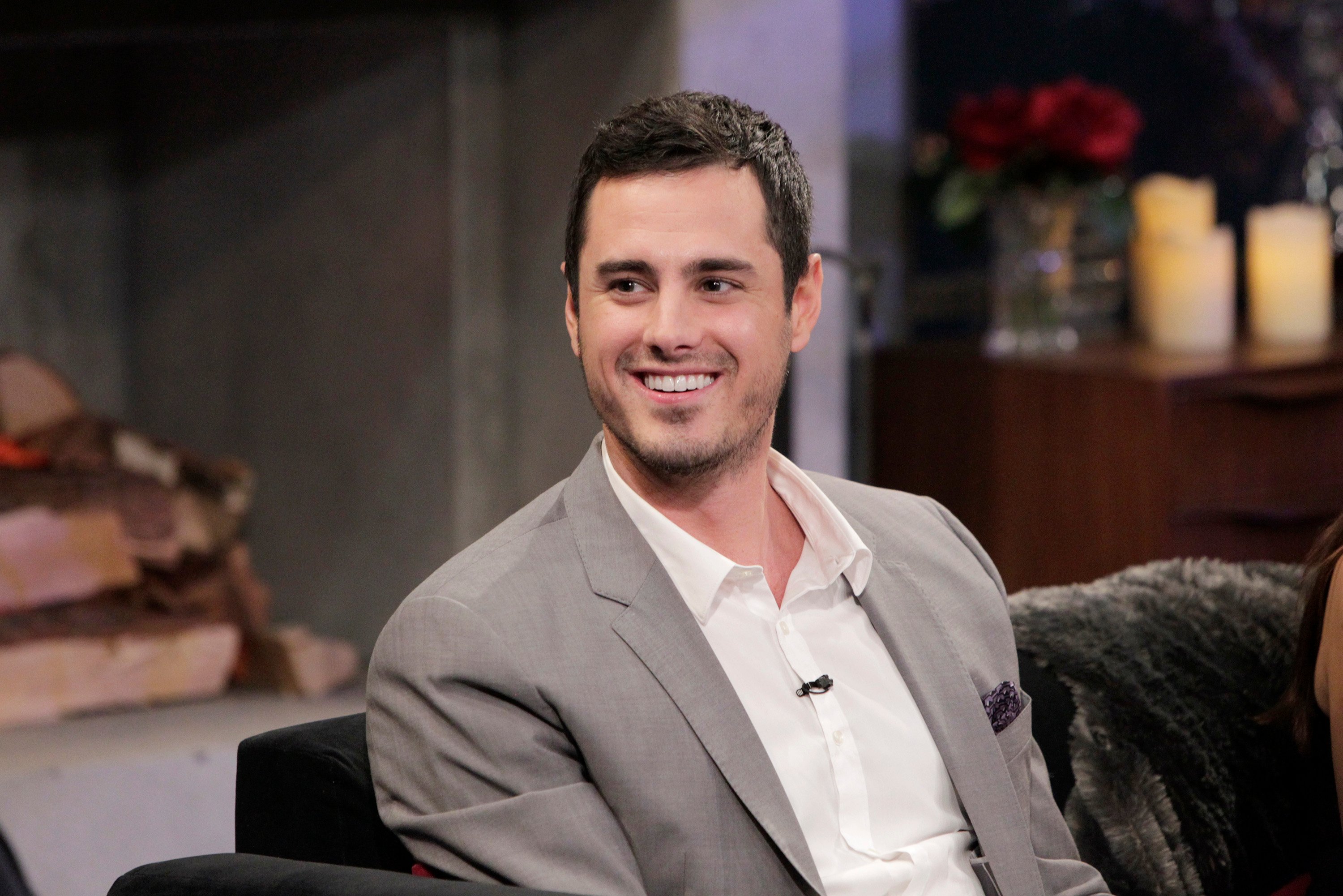 Ben Higgins sitting on a couch in grey blazer on "The Bachelor Live"