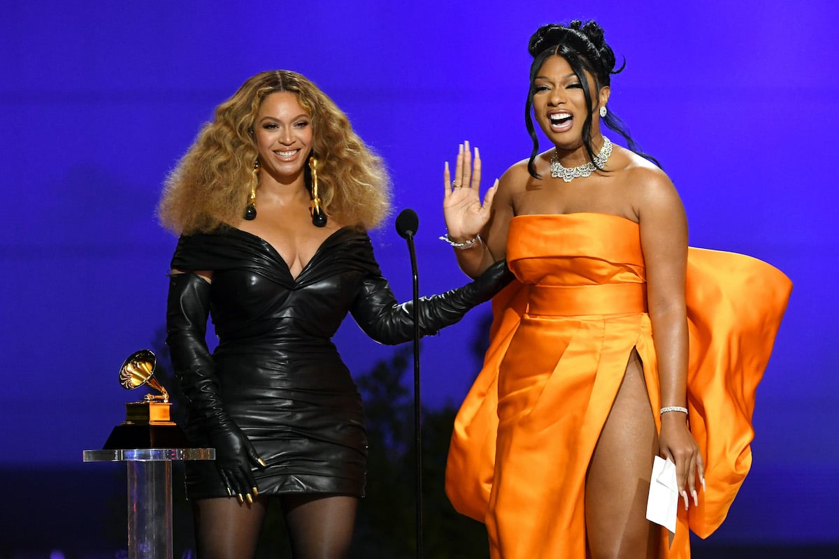 Beyoncé in a black dress and Megan Thee Stallion in an orange gown accepting the Grammy for Best Rap Performance at the 2021 Grammy Awards | Kevin Winter/Getty Images for The Recording Academy