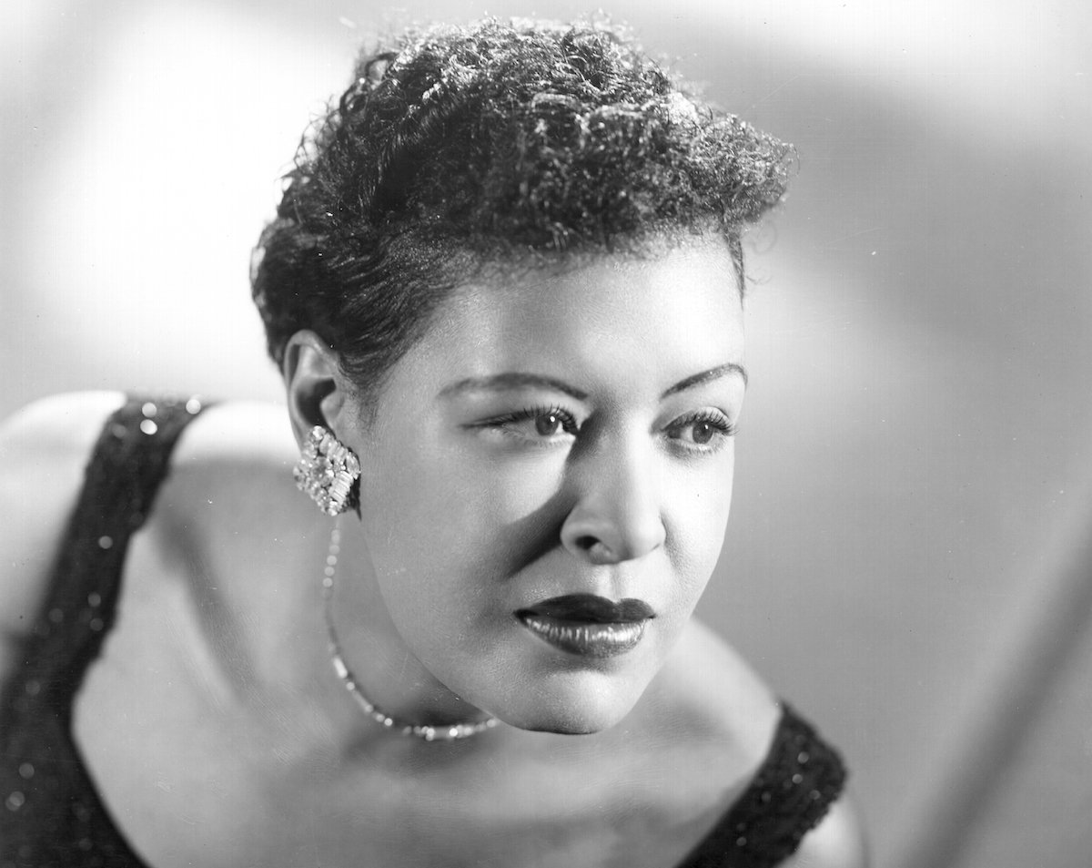 Black-and-white photo of Billie Holiday poses for a portrait in a sparkling black dress | Michael Ochs Archives/Getty Images