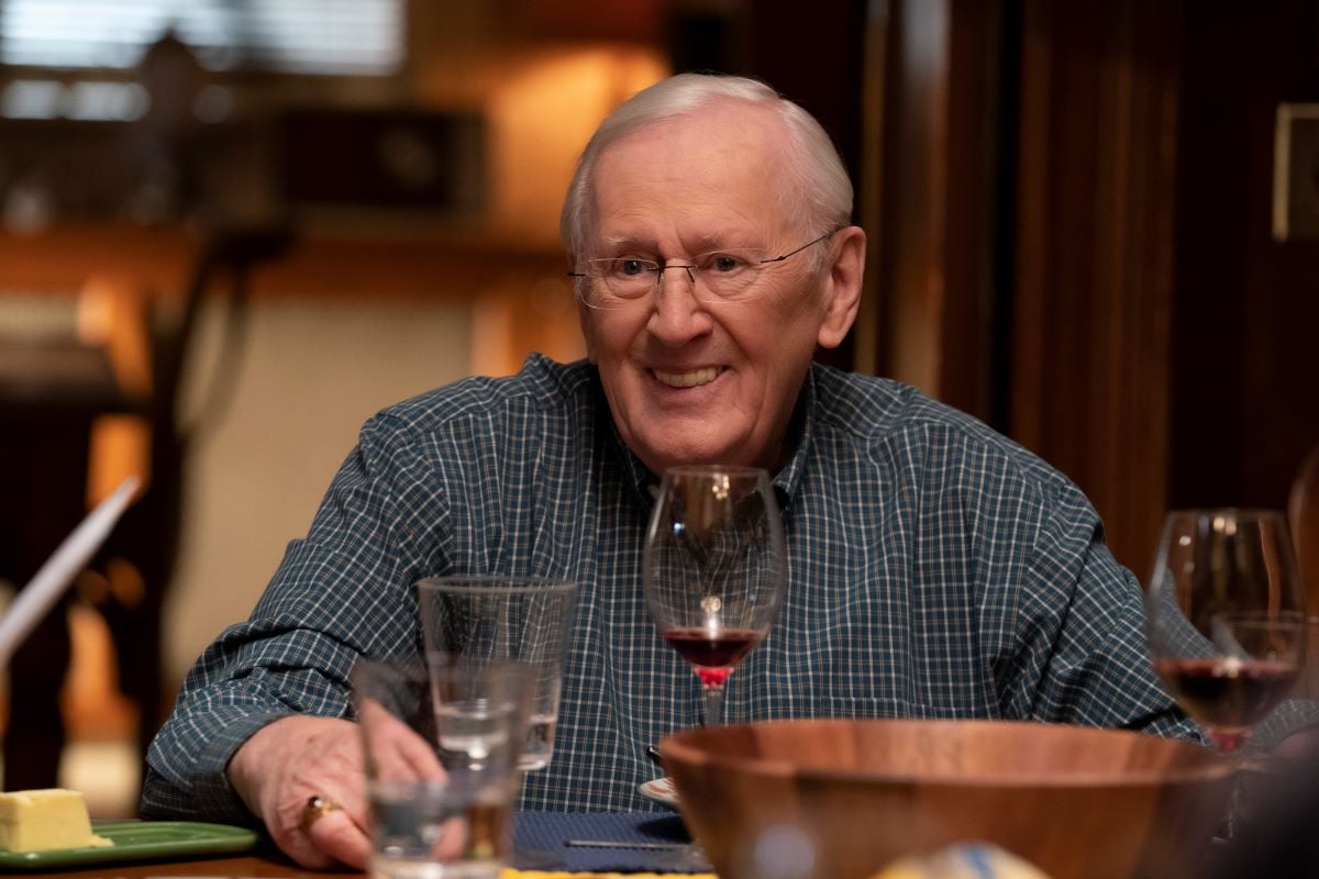 Len Cariou as Henry Cariou sits at the dinner table smiling in 'Blue Bloods