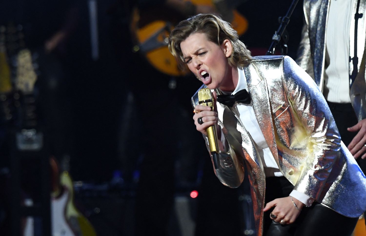 Singer Brandi Carlile performs on stage wearing a gold jacket.