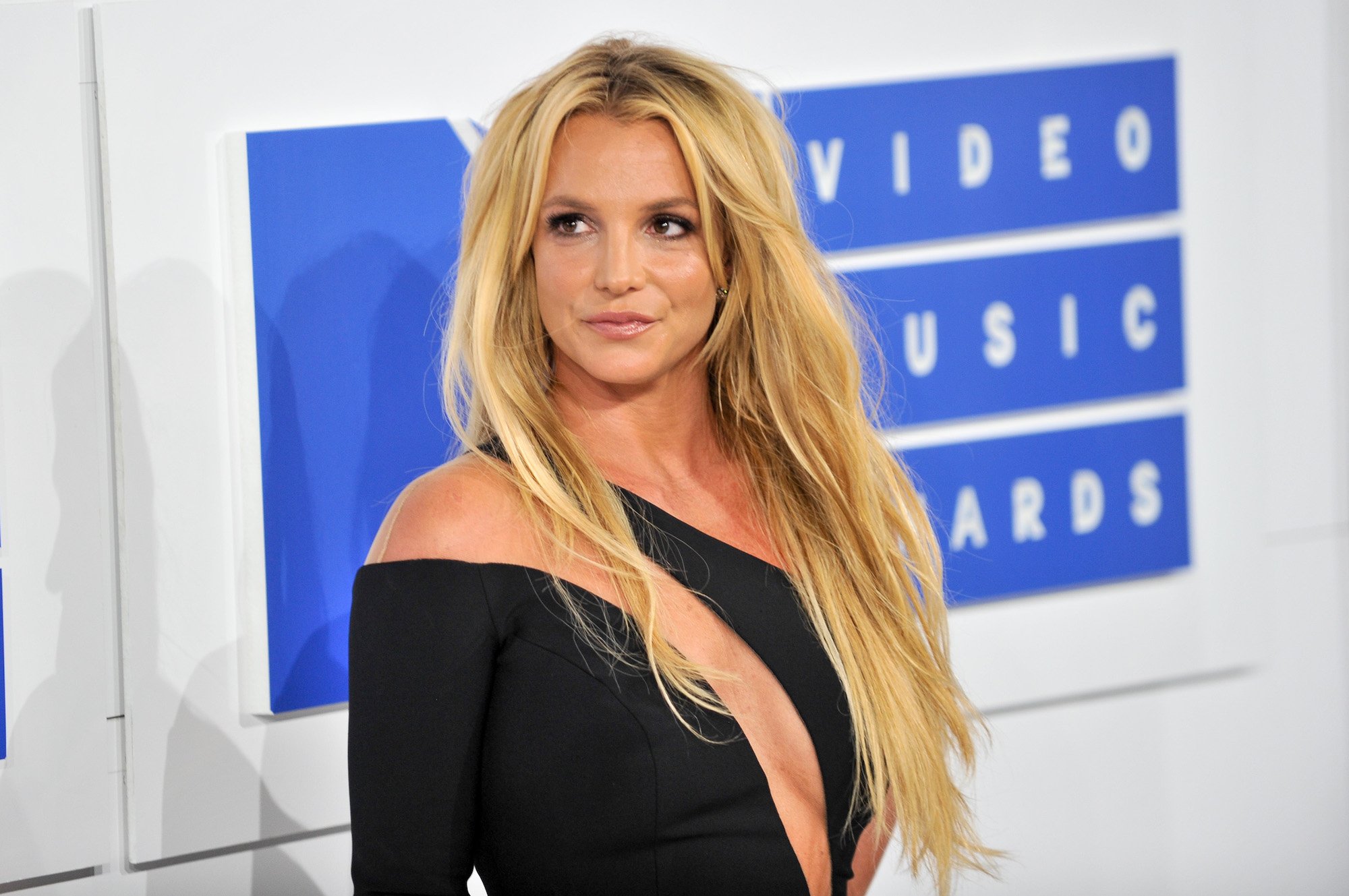 Britney Spears smiling in front of a blue and white background