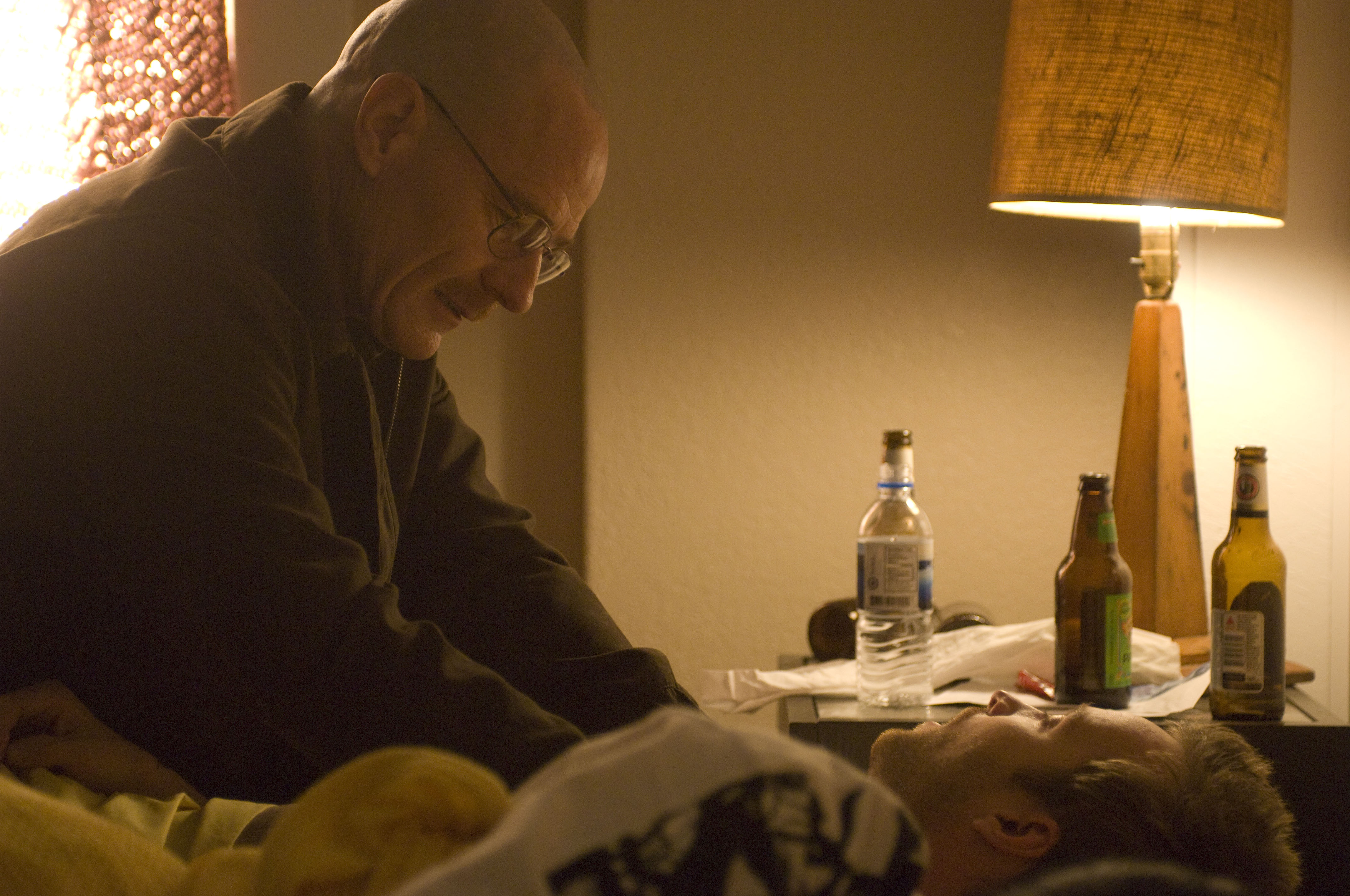 Bryan Cranston sitting next to Aaron Paul's bed