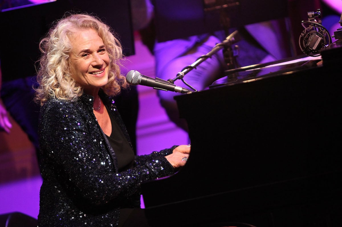 Carole King smiles as she sits at a piano and performs at the 2013 Library of Congress Gershwin Prize Tribute Concert