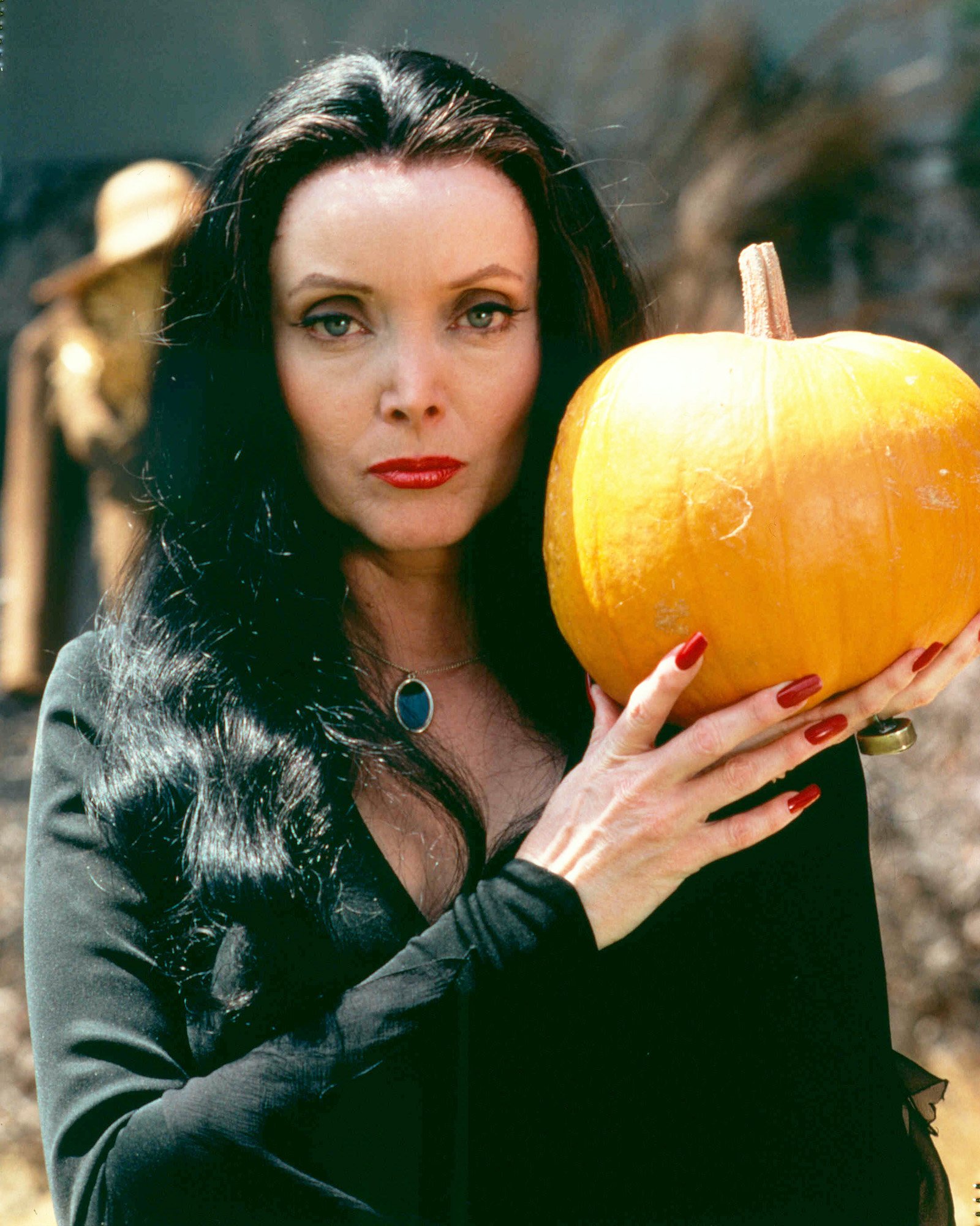 Carolyn Jones as Morticia Addams and holding a pumpkin