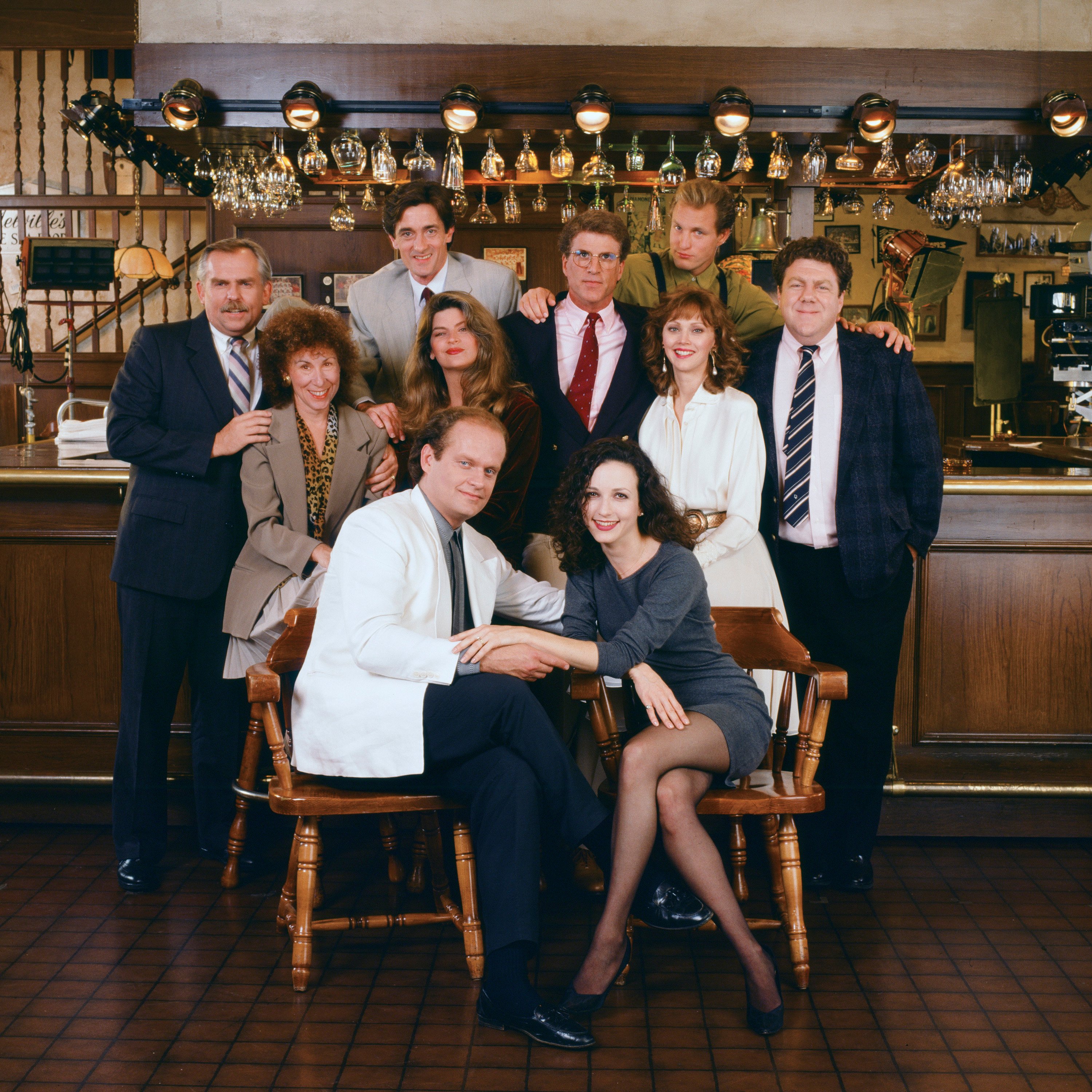 John Ratzenberger as Cliff Clavin, Rhea Perlman as Carla LeBec, Roger Rees as Robin Colcord, Kirstie Alley as Rebecca Howe, Kelsey Grammer as Dr. Frasier Crane, Ted Danson as Sam Malone, Bebe Neuwirth as Dr. Lilith Sternin-Crane, Shelley Long as Diane Chambers, Woody Harrelson as Woody Boyd, and George Wendt as Norm Peterson in a promotional photo for 'Cheers'