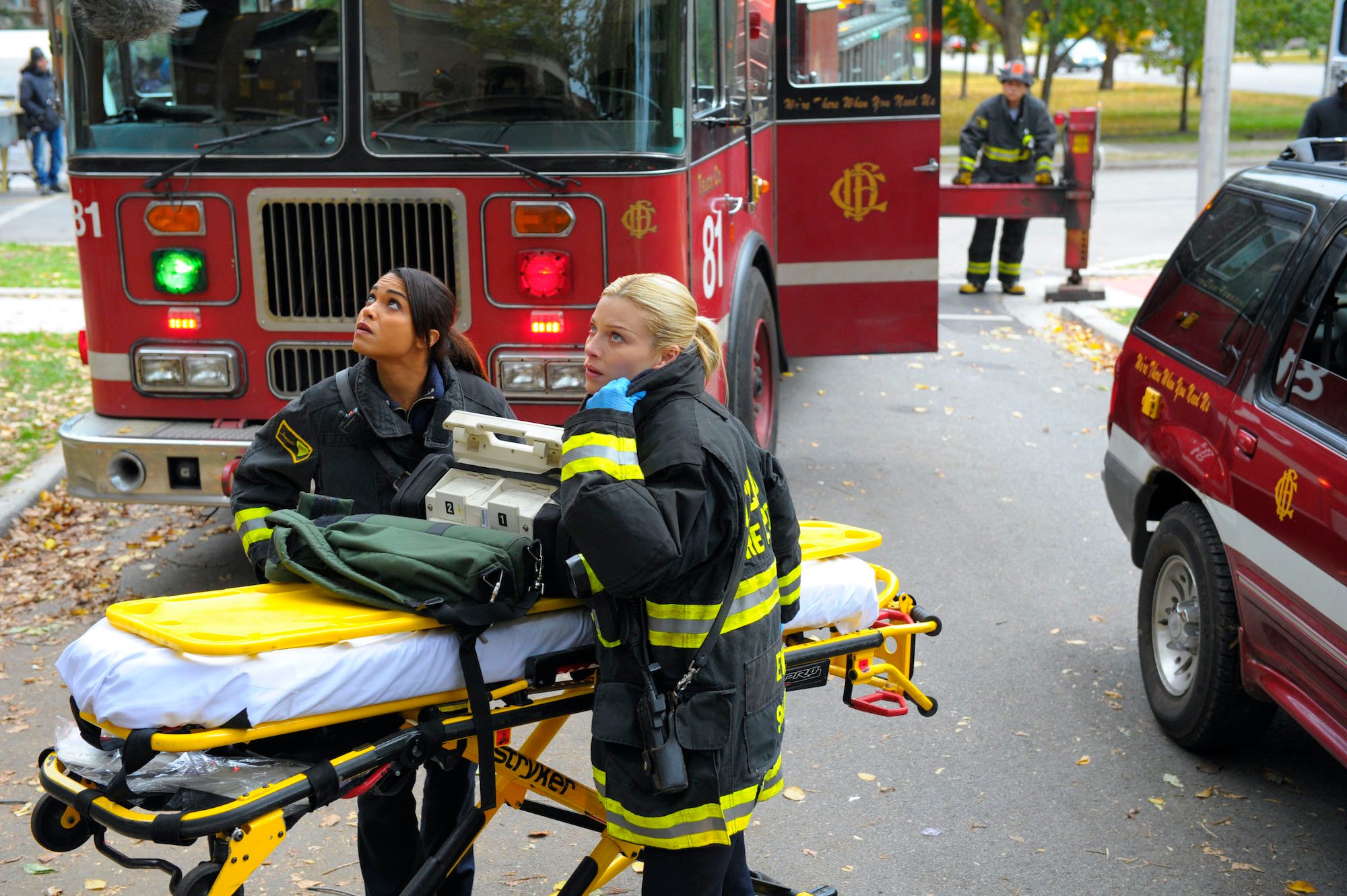 (L-R) Monica Raymund as Gabriella Dawson and Lauren German as Leslie Shay gathered around a stretcher in front of fire trucks