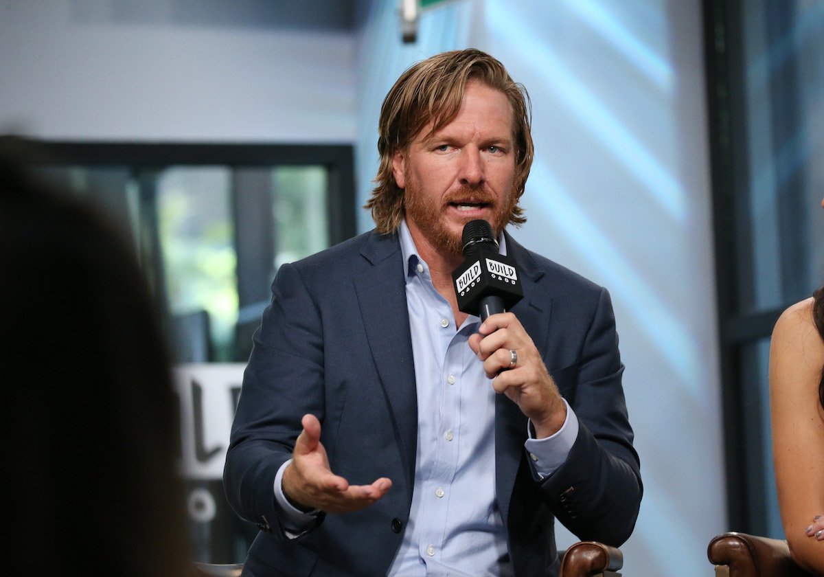 Chip Gaines is holding a microphone and talking on stage