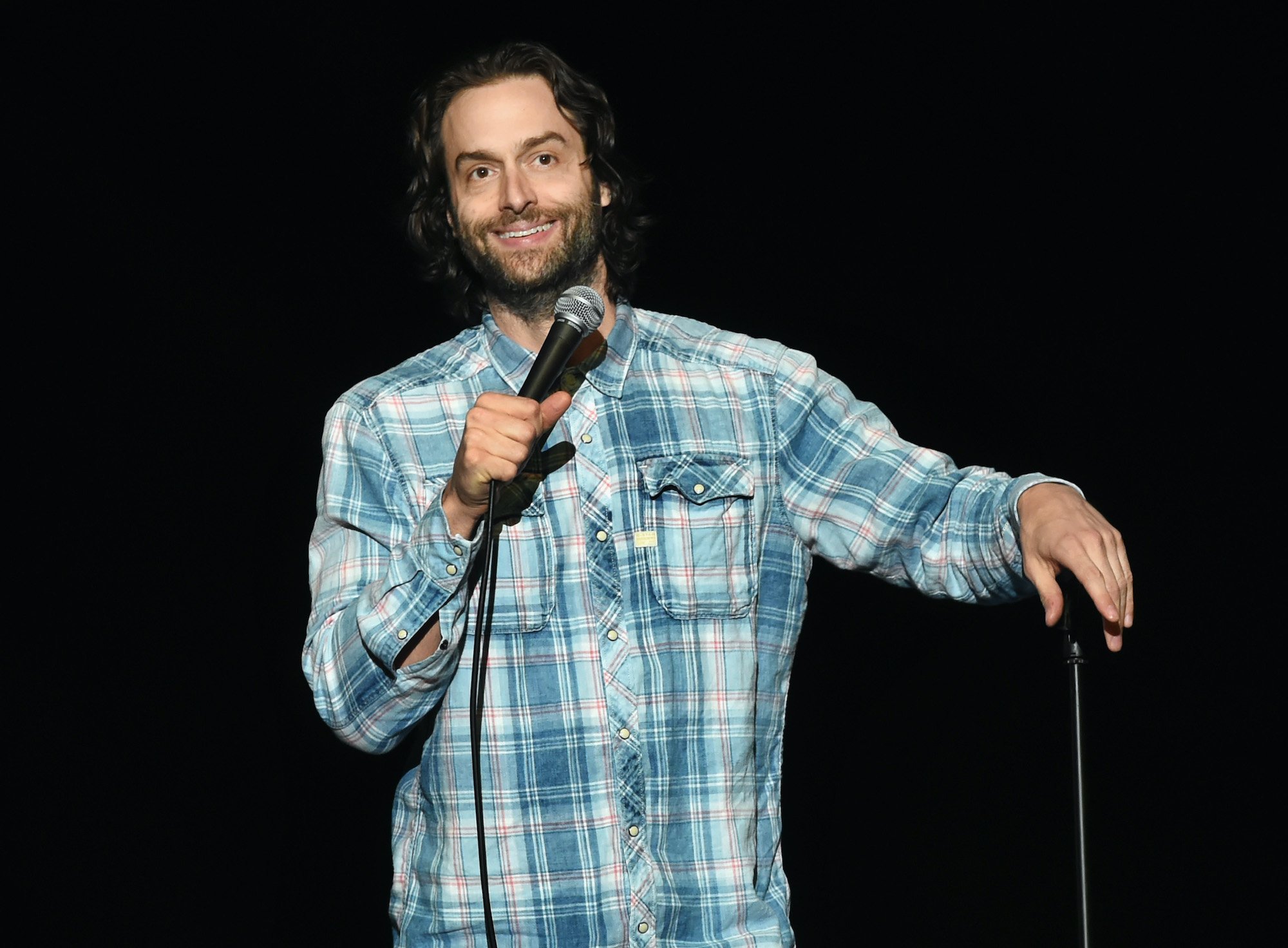Chris D'Elia smiling in front of a black background