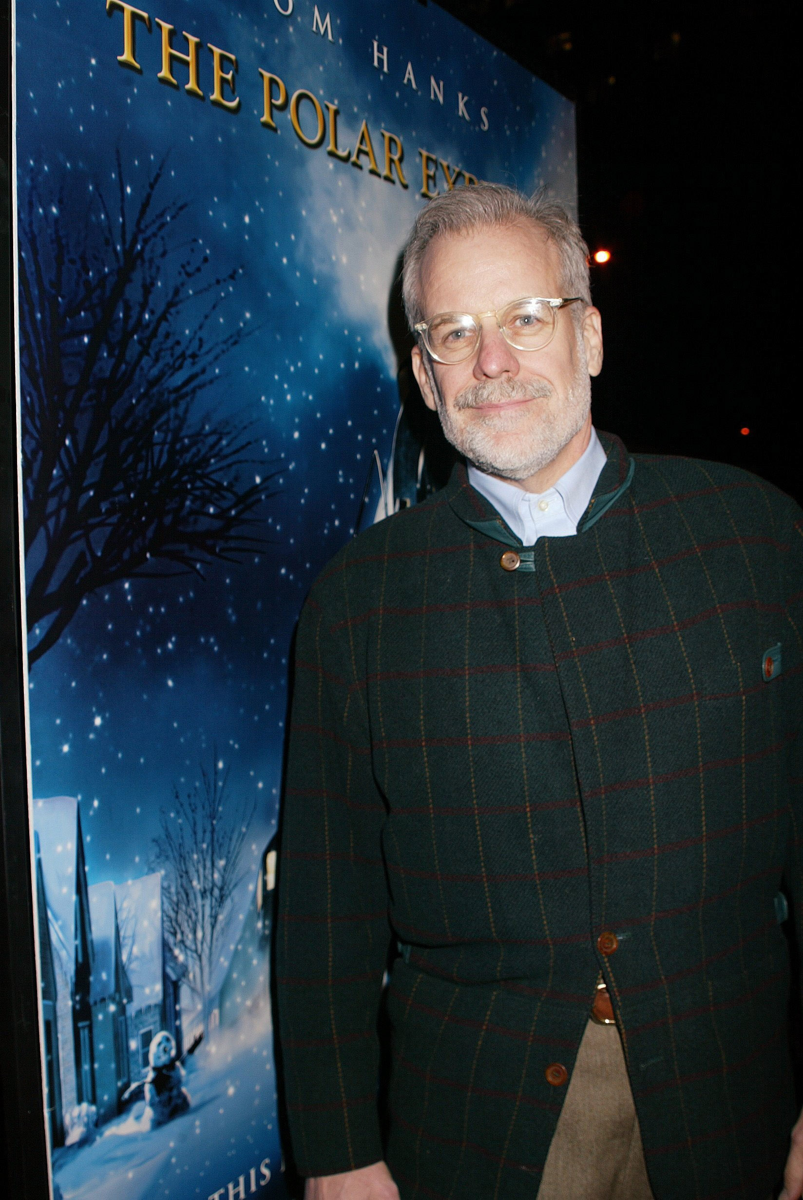 Chris Van Allsburg stands next to a Polar Express poster